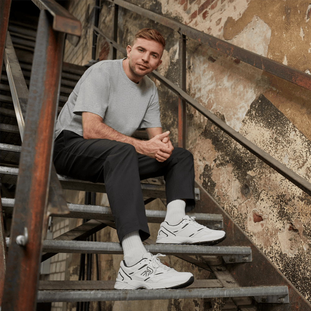Christoph Kramer sitzt auf einer Treppe mit Rieker Sport Schuhen