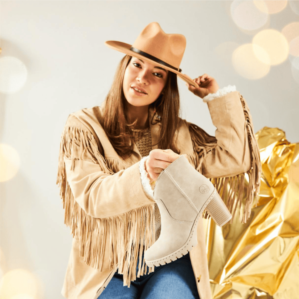 Une femme tient des bottines de cowboy y2553-60 de Rieker.