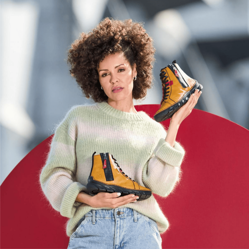 Une femme tient des chaussures 55024-68 de Rieker.