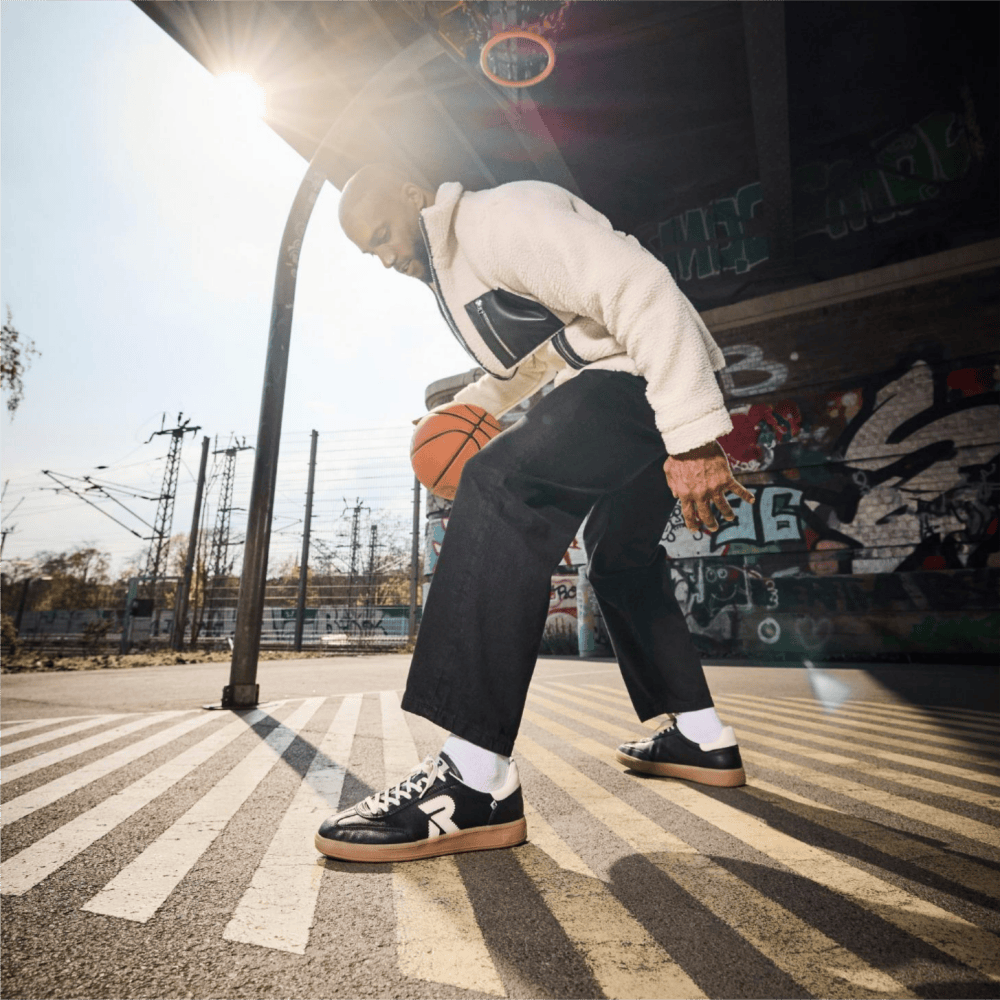 Homme dansant le breakdance, s\'appuyant d\'une main sur le sol et portant des Sneakers San Diego U2200-00 de Rieker.