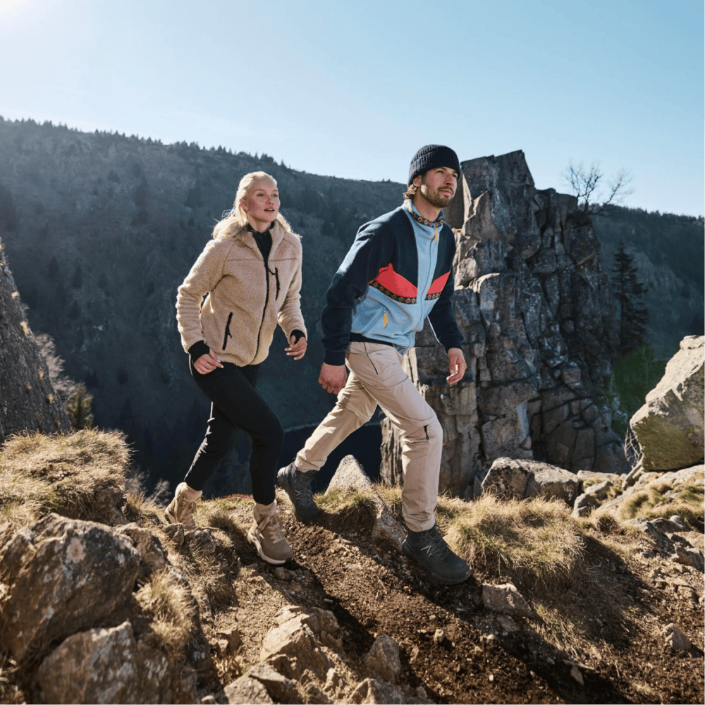 La femme et l\'homme font de la randonnée sur une montagne avec les baskets de Rieker pour hommes et femmes.
