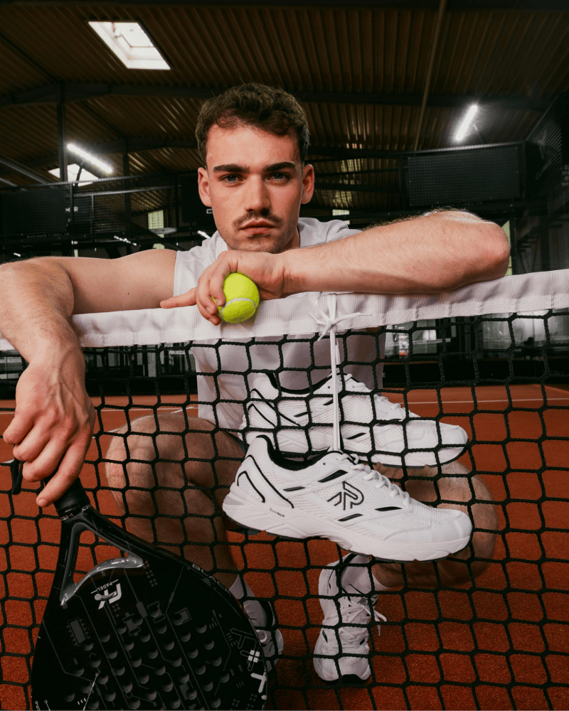 Mann mit Padel Schläger Ball und sportlichen Rieker Sneaker in schwaz-weiss