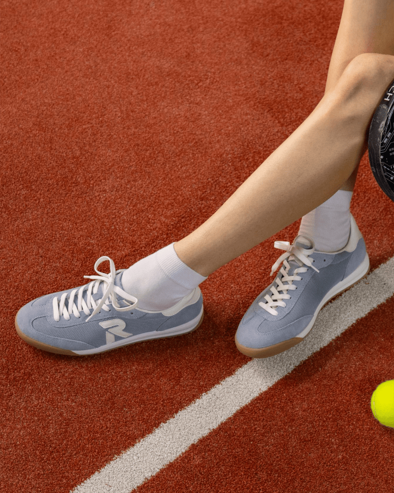 sportliche Damen Retro Sneaker in hellblau auf einem Padel Court