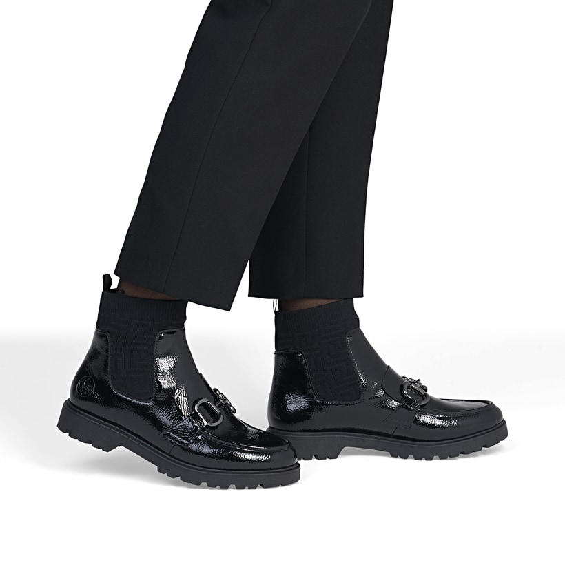 Schwarze Rieker Damen Kurzstiefel 45573-00 mit Schmuckelementen sowie Gummizug. Schuh am Fuß.