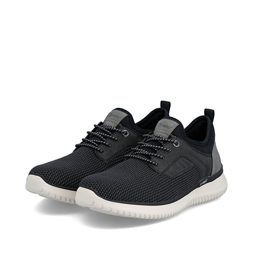 Schwarze Rieker Herren Slipper B9651-00 mit einem Gummizug sowie Komfortweite G. Schuhpaar seitlich schräg.