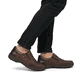Braune Rieker Herren Slipper 03354-26 mit einem Gummizug sowie der Extraweite H. Schuh am Fuß.