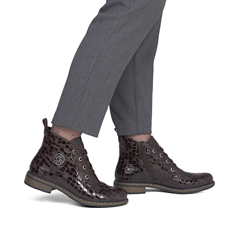 Dunkelbraune Rieker Damen Schnürstiefel 71205-25 mit auffälligem Logo. Schuh am Fuß.