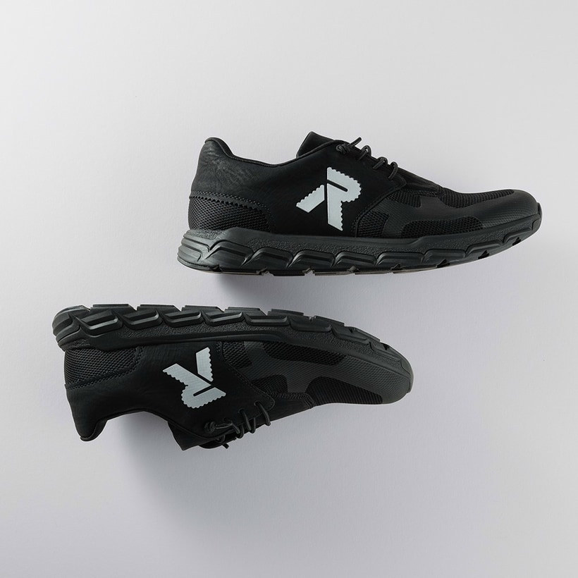 Schwarze Rieker Herren Sneaker Low 09100-00 mit einer Gummischnürung. Schuhpaar seitlich liegend auf grauem Hintergrund.