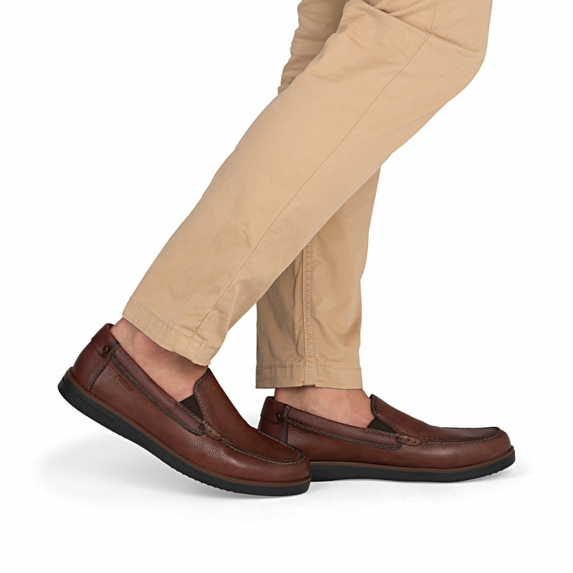 Braune Rieker Herren Slipper B2352-24 aus Glattleder mit modernen Ziernähten. Schuh am Fuß.