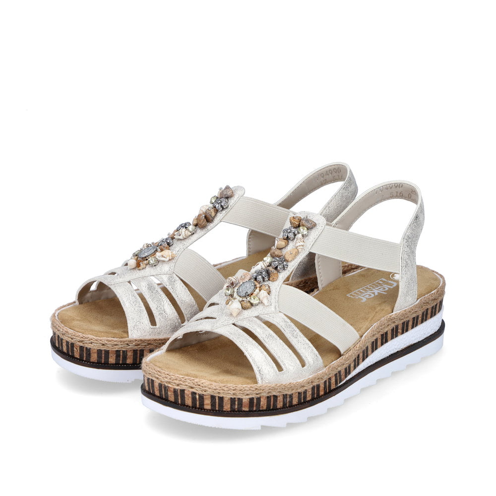 Sandales compensées Rieker or femme V7949-90 avec éléments décoratifs. Chaussures inclinées sur le côté.