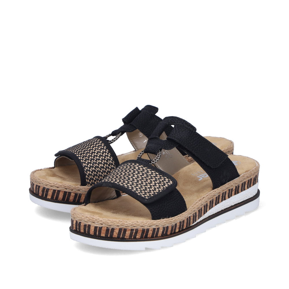 Schwarze Rieker Damen Pantoletten V7947-00 mit einem Klettverschluss. Schuhpaar seitlich schräg.
