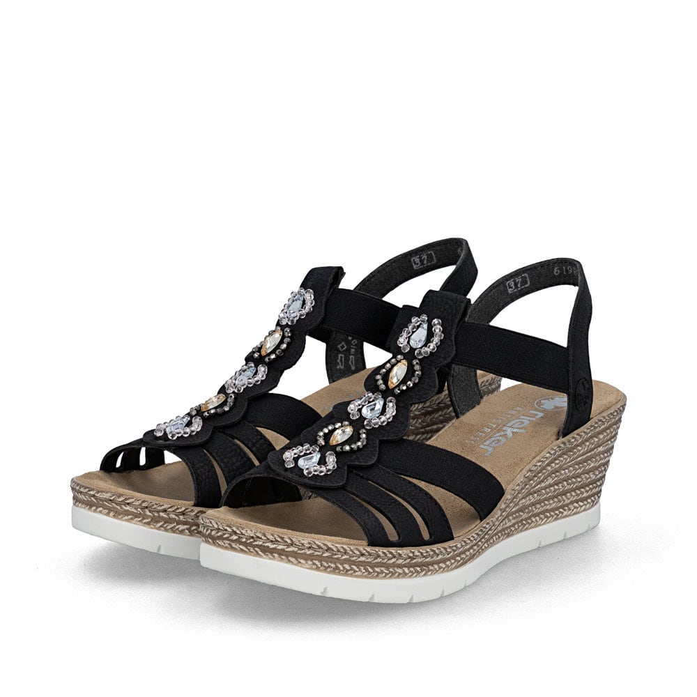 Schwarze Rieker Keilsandaletten 619B2-00 mit Schmuckelementen sowie Gummizug. Schuhpaar seitlich schräg.