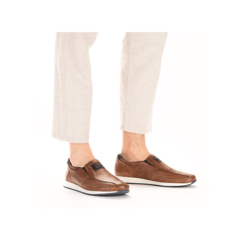 Braune Rieker Herren Slipper 11962-25 aus Glattleder mit modernen Ziernähten. Schuh am Fuß.