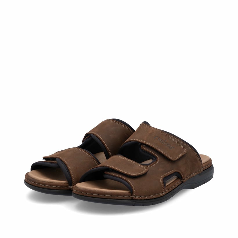 Mules Rieker marron homme 25559-25 en cuir velours avec fermeture velcro. Chaussures inclinées sur le côté.