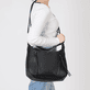 Sac bandoulière Rieker H1016-00 en noir avec fermeture éclair ainsi que poches extérieures et intérieures. Porté.