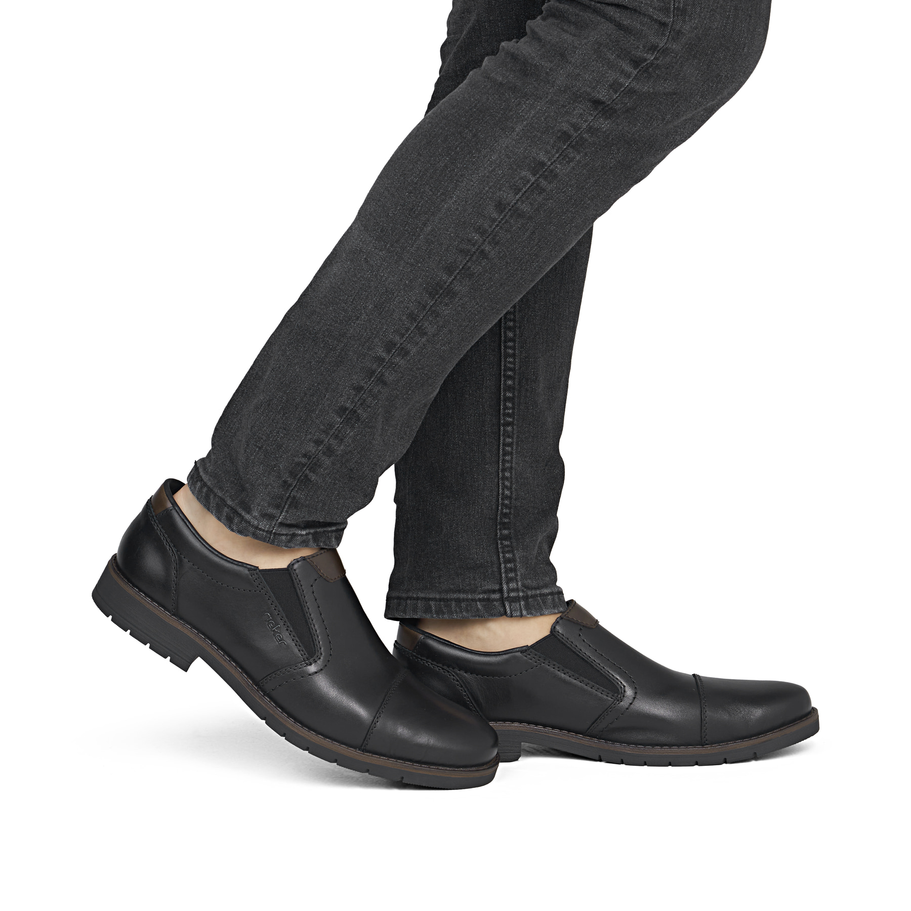 Mocassins Rieker noirs hommes 13950-00 en cuir lisse avec bande élastique. Chaussure au pied.