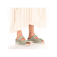 Grüne Rieker Damen Pantoletten V7492-52 mit Klettverschluss sowie Extraweite H. Schuh am Fuß.