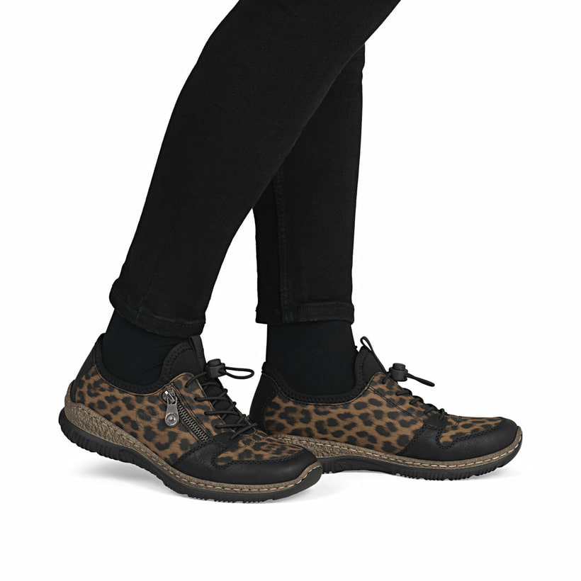 Braunschwarze Rieker Damen Slipper N32G0-90 mit Leo-Print sowie einem Gummizug. Schuh am Fuß.