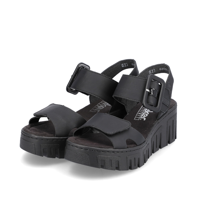 Schwarze vegane Rieker Keilsandaletten 68050-00 mit trendigen Schnalle. Schuhpaar seitlich schräg.
