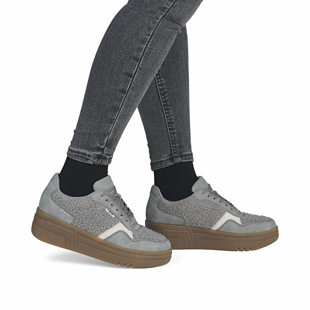 Graue Rieker Damen Sneaker Low M7600-40 mit Teddyfell-Details sowie Schnürung. Schuh am Fuß.