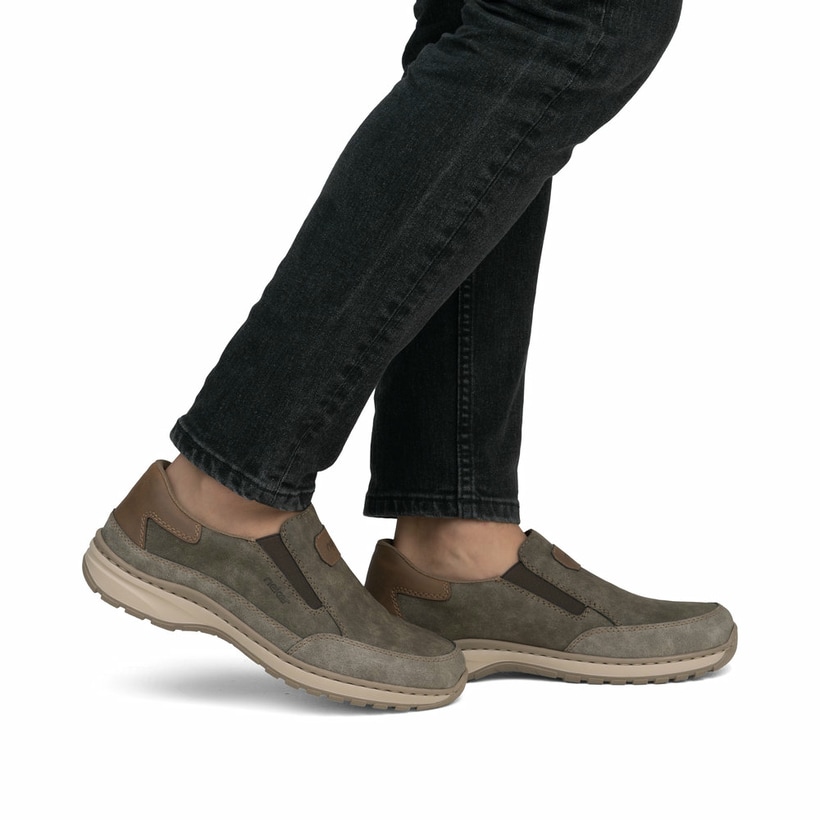 Braune Rieker Herren Slipper 03365-25 mit einem Gummizug sowie der Extraweite H. Schuh am Fuß.