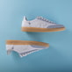 Weiße Rieker Damen Sneaker Low W2200-84 mit einer Schnürung. Schuh seitlich schräg. Schuhpaar seitlich liegend auf blauem Hintergrund.