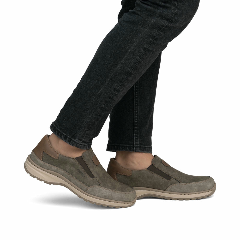 Braune Rieker Herren Slipper 03365-25 mit einem Gummizug sowie der Extraweite H. Schuh am Fuß.
