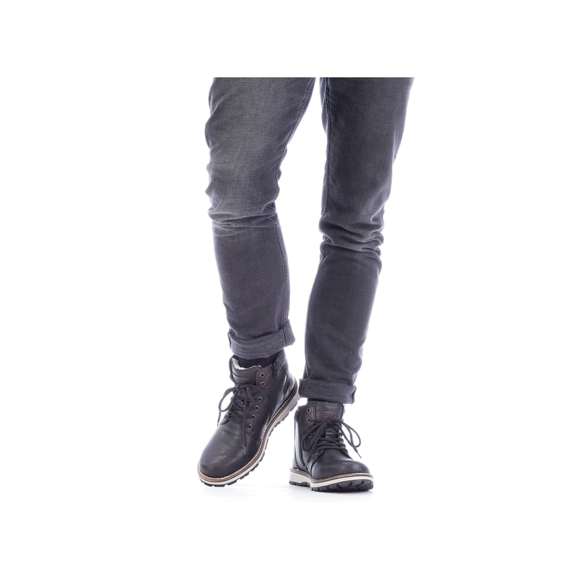 Asphaltschwarze Rieker Herren Schnürstiefel 38441-01 mit einer robusten Profilsohle. Schuh am Fuß