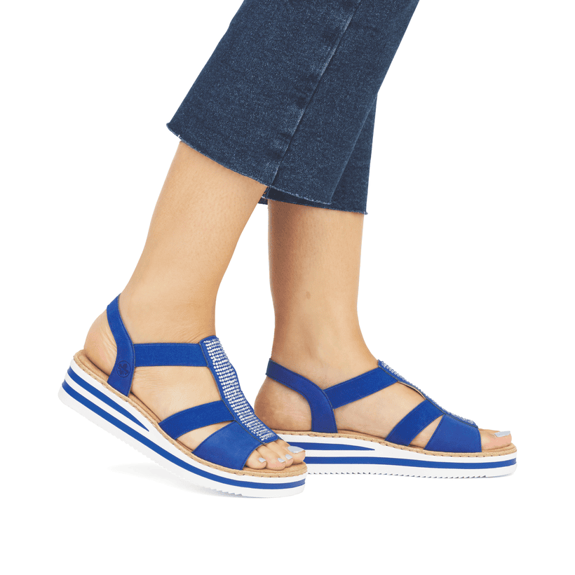 Blaue Rieker Keilsandaletten V0209-14 mit Elastikeinsatz sowie Schmuckelementen. Schuh am Fuß.