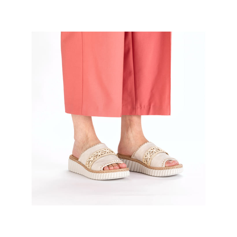 Beige Rieker Damen Pantoletten 69278-60 mit Schmuckelementen sowie Extraweite H. Schuh am Fuß.