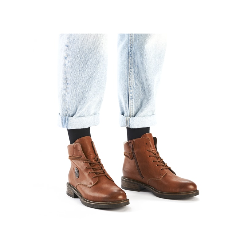 Braune Rieker Damen Schnürstiefel 71440-25 mit rundem Logo sowie Reißverschluss. Schuh am Fuß.