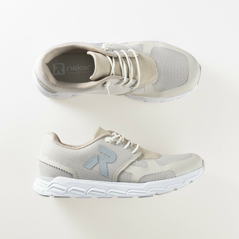 Beige Rieker Damen Sneaker Low M9000-60 mit Gummischnürung sowie flexibler Sohle. Schuhpaar von oben, seitlich auf beigem Hintergrund.