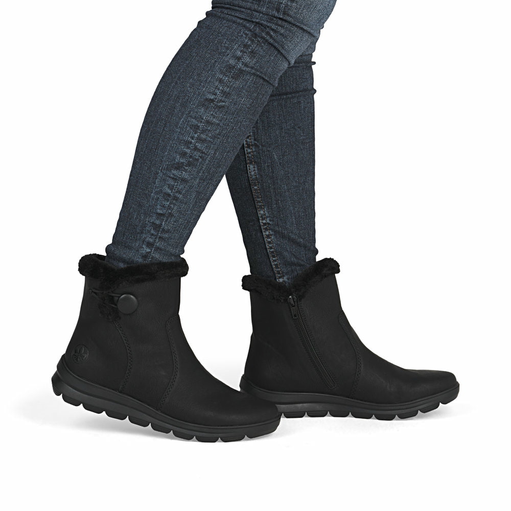 Tiefschwarze Rieker Damen Kurzstiefel Z0080-00 mit Fellschaftrand. Schuh am Fuß.