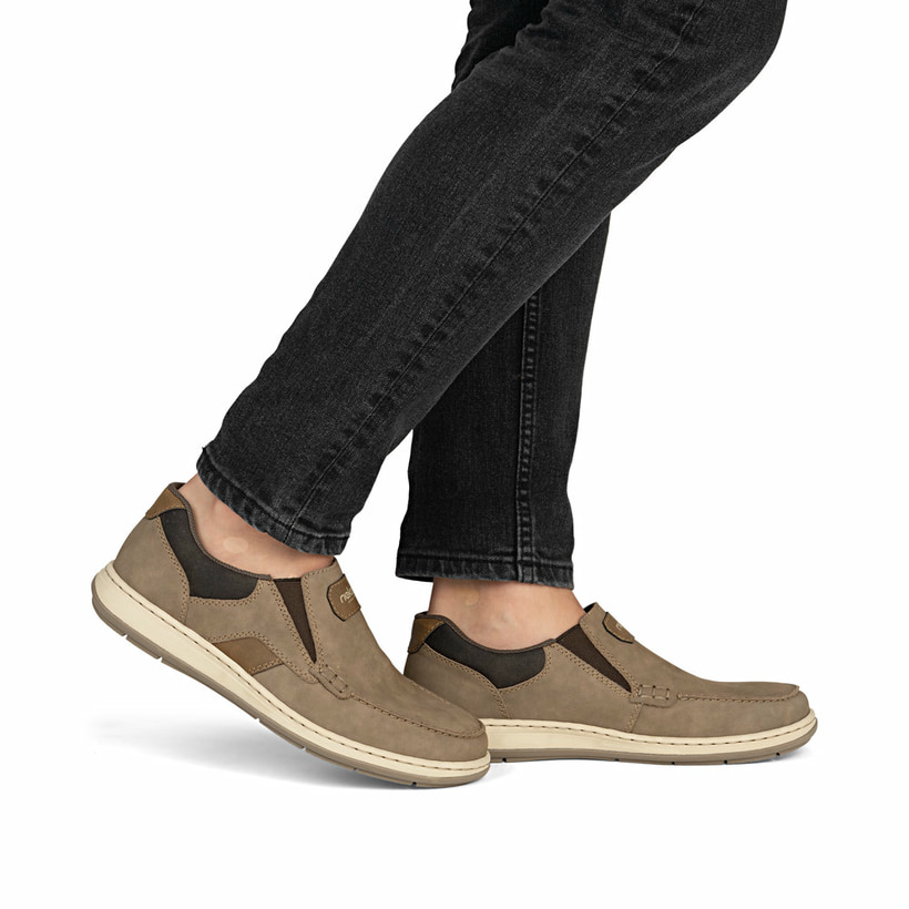 Braune Rieker Herren Slipper 17368-25 mit einem Gummizug sowie der Extraweite H. Schuh am Fuß.