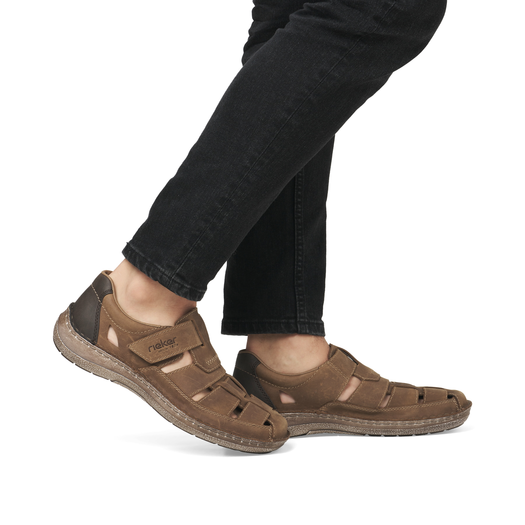 Braune Rieker Herren Slipper 03078-25 mit Klettverschluss sowie der Extraweite H. Schuh am Fuß.