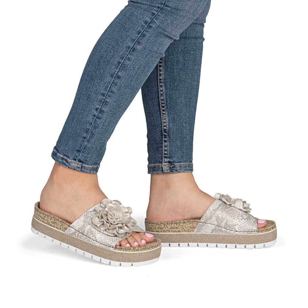 Mules Rieker dorées pour femme 69562-90 avec fleur décorative. Chaussure au pied.