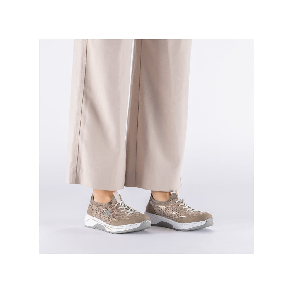 Beige Rieker Damen Slipper 53151-64 mit metallischem Finish sowie einem Gummizug. Schuh am Fuß.