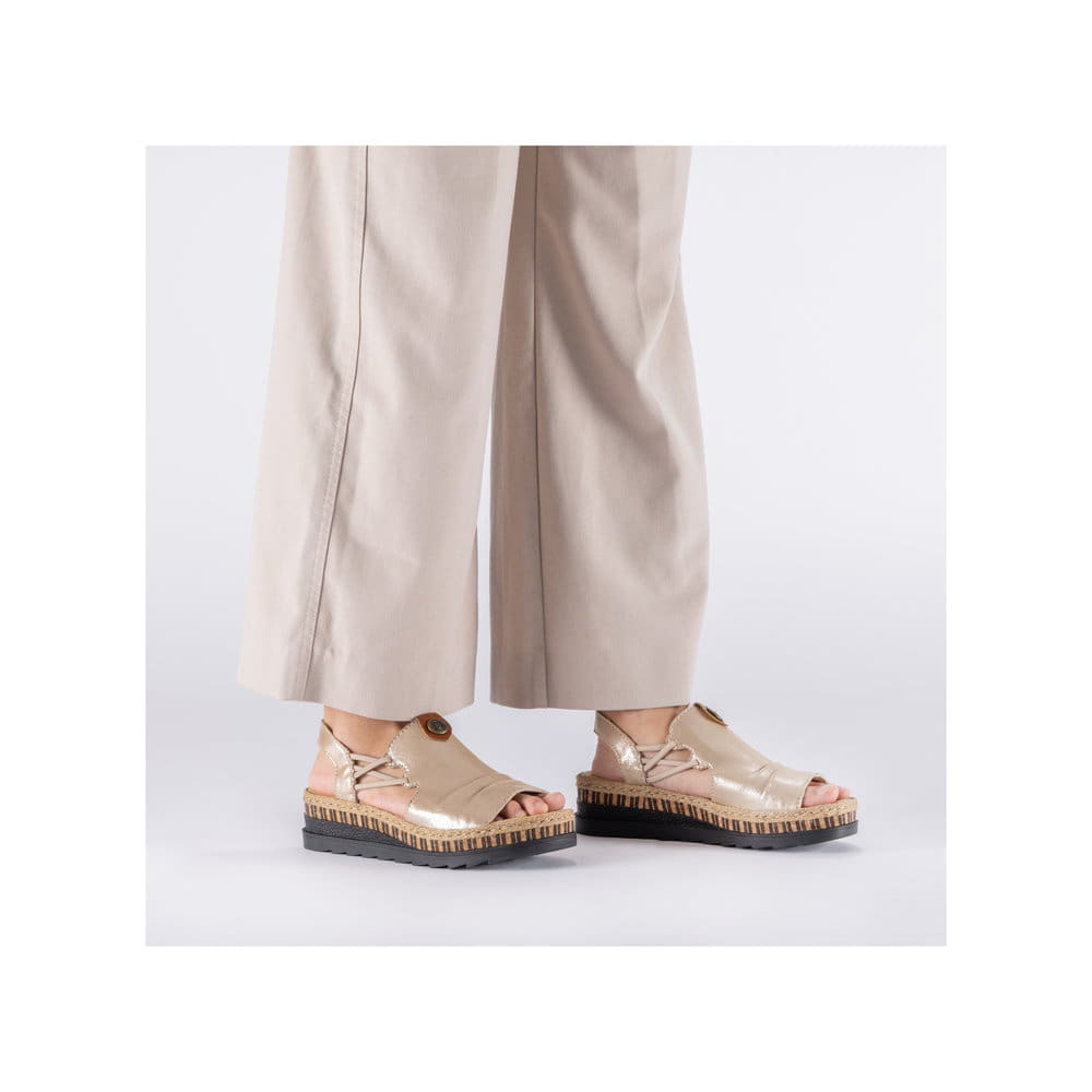 Beige Rieker Keilsandaletten V7972-60 mit metallischem Finish sowie Gummizug. Schuh am Fuß.