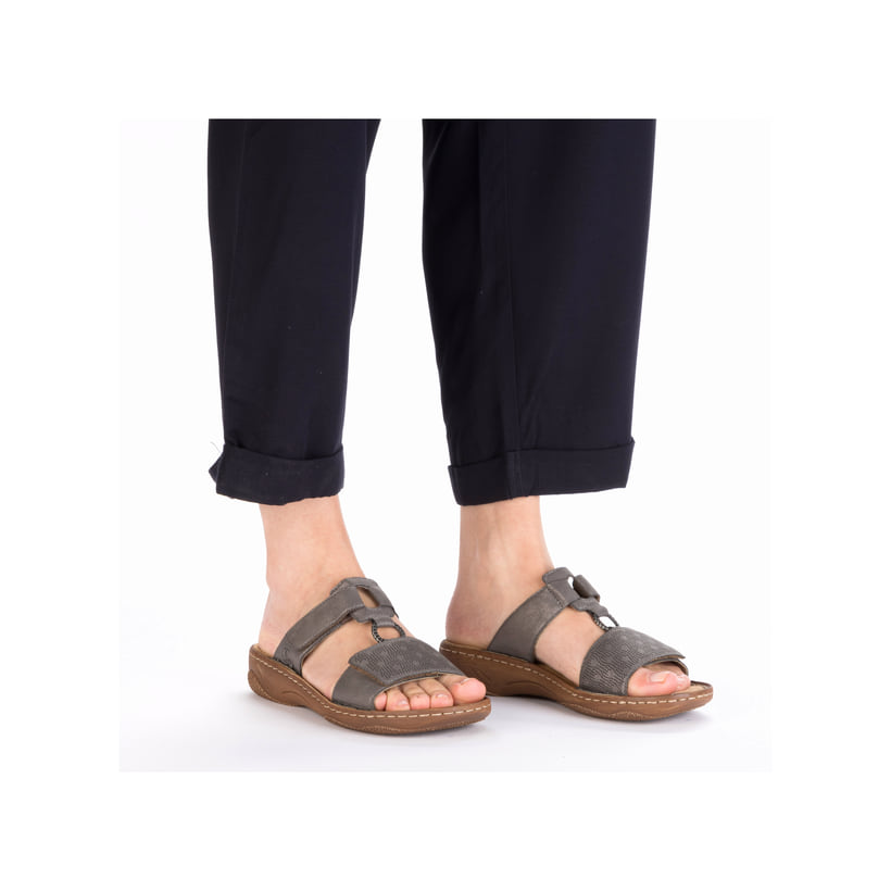 Graue Rieker Damen Pantoletten V2885-42 in Löcheroptik mit einem Klettverschluss. Schuh am Fuß.