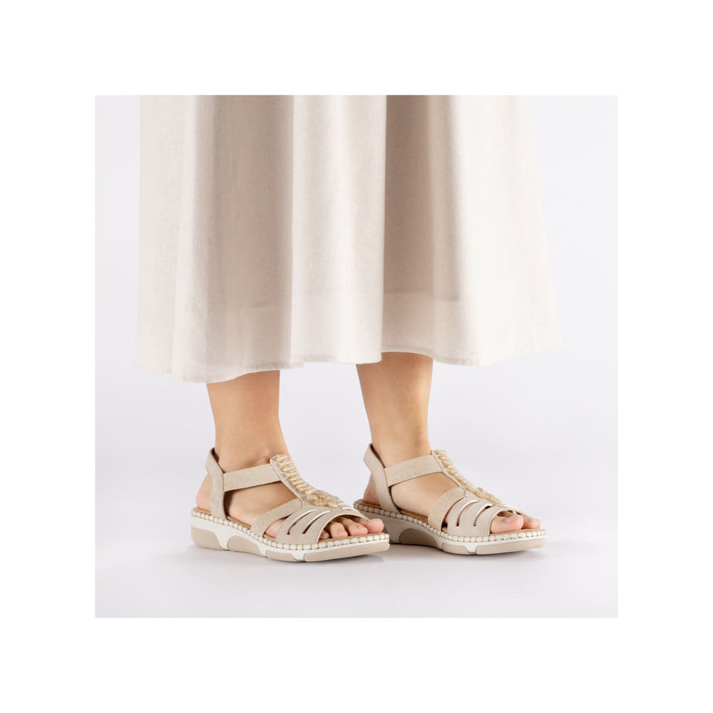 Beige Rieker Damen Riemchensandalen 66201-62 mit Schmuckelementen sowie Gummizug. Schuh am Fuß.