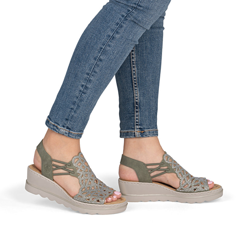 Khakifarbene Rieker Keilsandaletten 67465-52 mit Strasssteinen sowie Gummizug. Schuh am Fuß.
