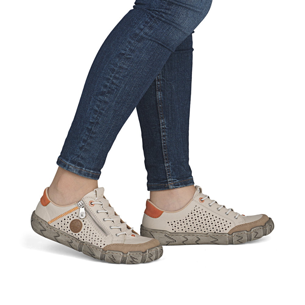 Beige Rieker Damen Slipper L0355-61 aus Glattleder mit eleganten Zierlochungen. Schuh am Fuß.