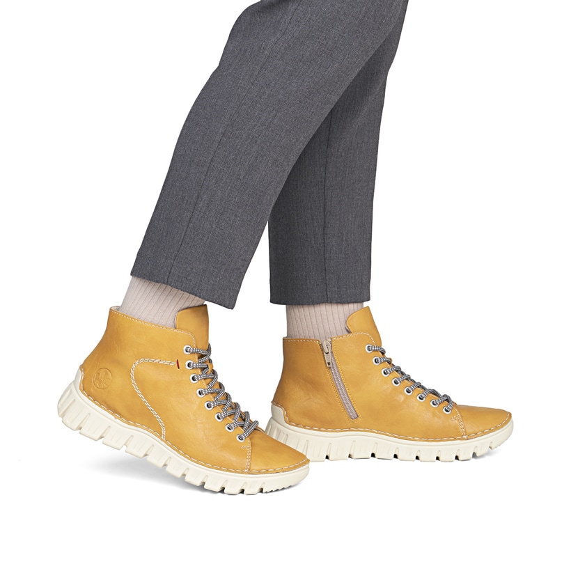 Ockerfarbene Rieker Damen Schnürstiefel 57501-68 mit modernen Ziernähten. Schuh am Fuß.