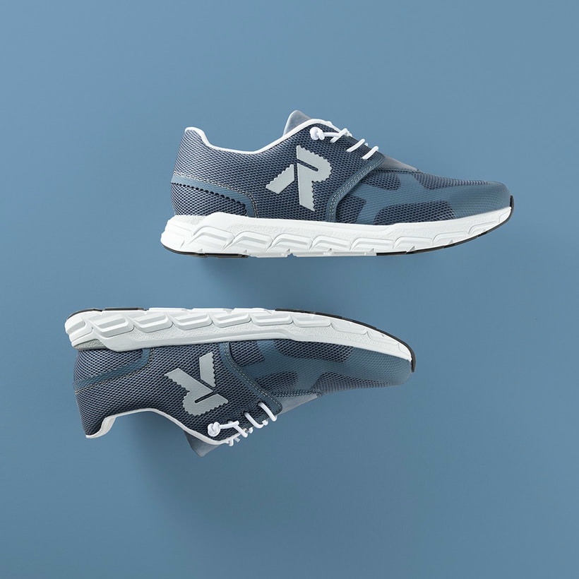 Blaue Rieker Damen Sneaker Low M9000-12 mit Gummischnürung sowie flexibler Sohle. Schuhpaar seitlich liegend auf blauem Hintergrund.
