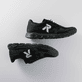 Schwarze Rieker Herren Sneaker Low 09100-00 mit einer Gummischnürung. Schuhpaar seitlich liegend auf grauem Hintergrund.