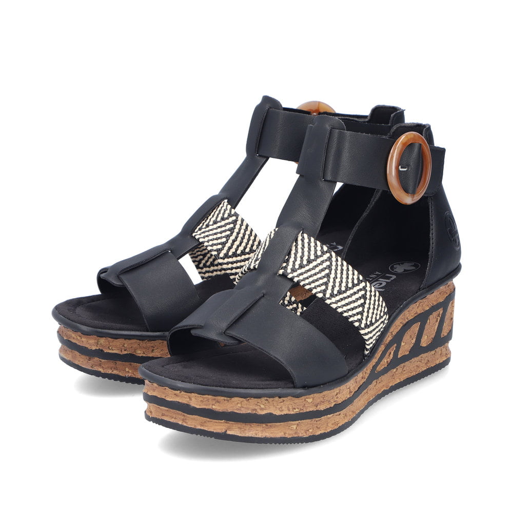 Schwarze Rieker Keilsandaletten 68182-00 mit trendiger Schnalle. Schuhpaar seitlich schräg.