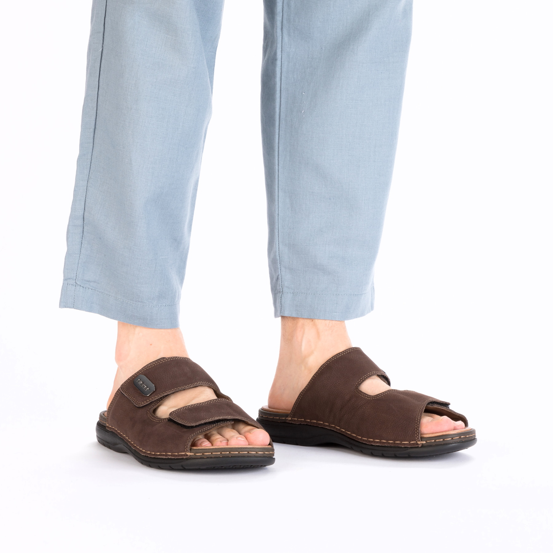 Mules Rieker marron homme 25590-25 en cuir lisse avec fermeture velcro. Chaussure au pied.