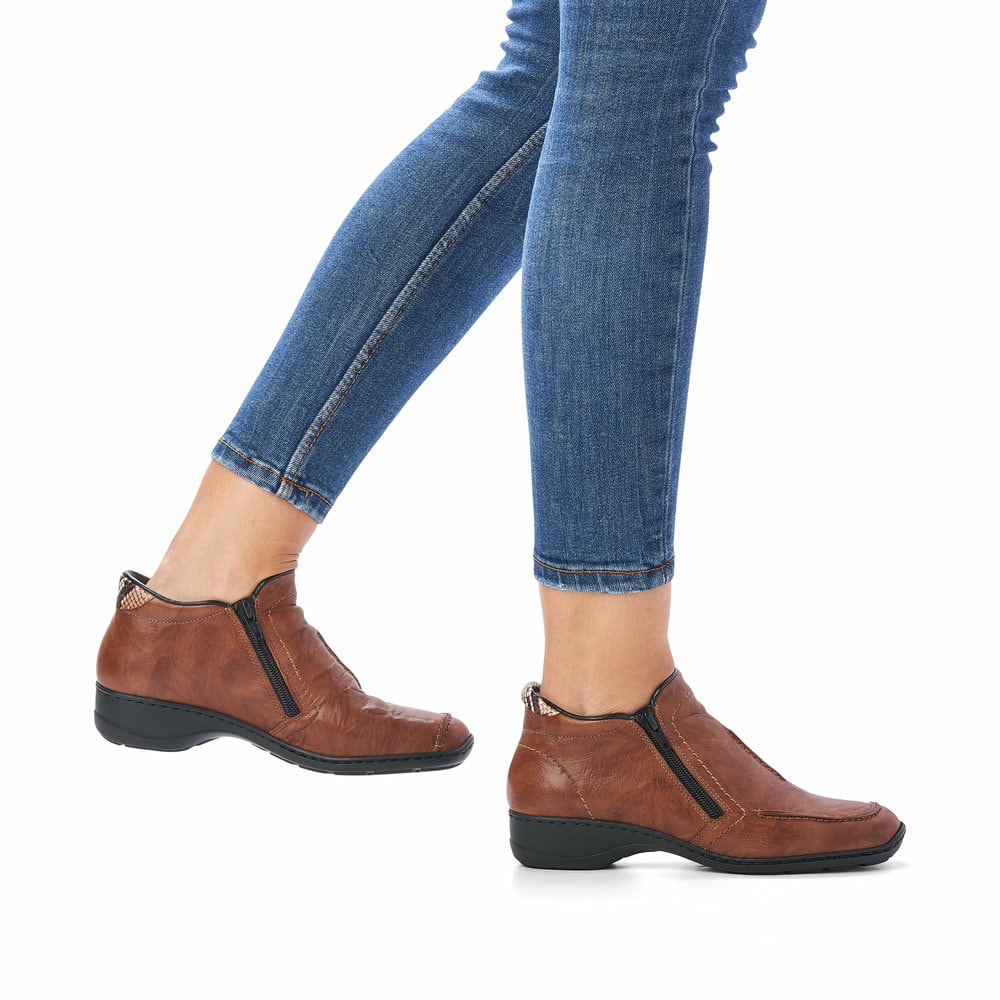 Braune Rieker Damen Kurzstiefel 58386-22 aus Glattleder mit einem Reißverschluss. Schuh am Fuß.