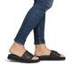 Schwarze Rieker Damen Pantoletten W1453-00 mit Gummizug sowie trendigen Schnalle. Schuh am Fuß.