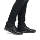 
Tiefschwarze Rieker Herren Slipper 14454-01 mit Elastikeinsatz sowie einer Profilsohle. Schuh am Fuß